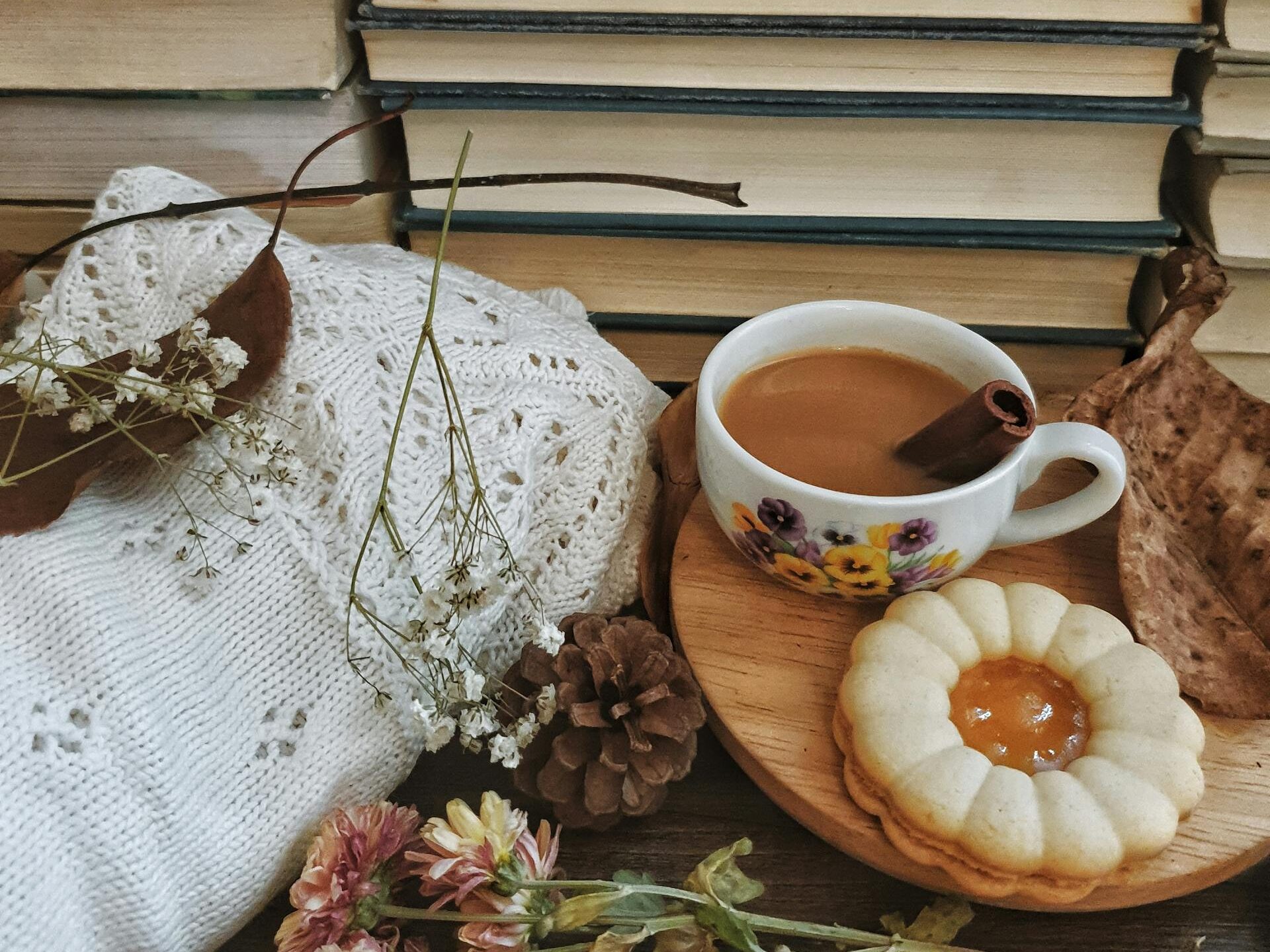 Warm and inviting autumn scene featuring a coffee cup, stack of books, and cozy elements.